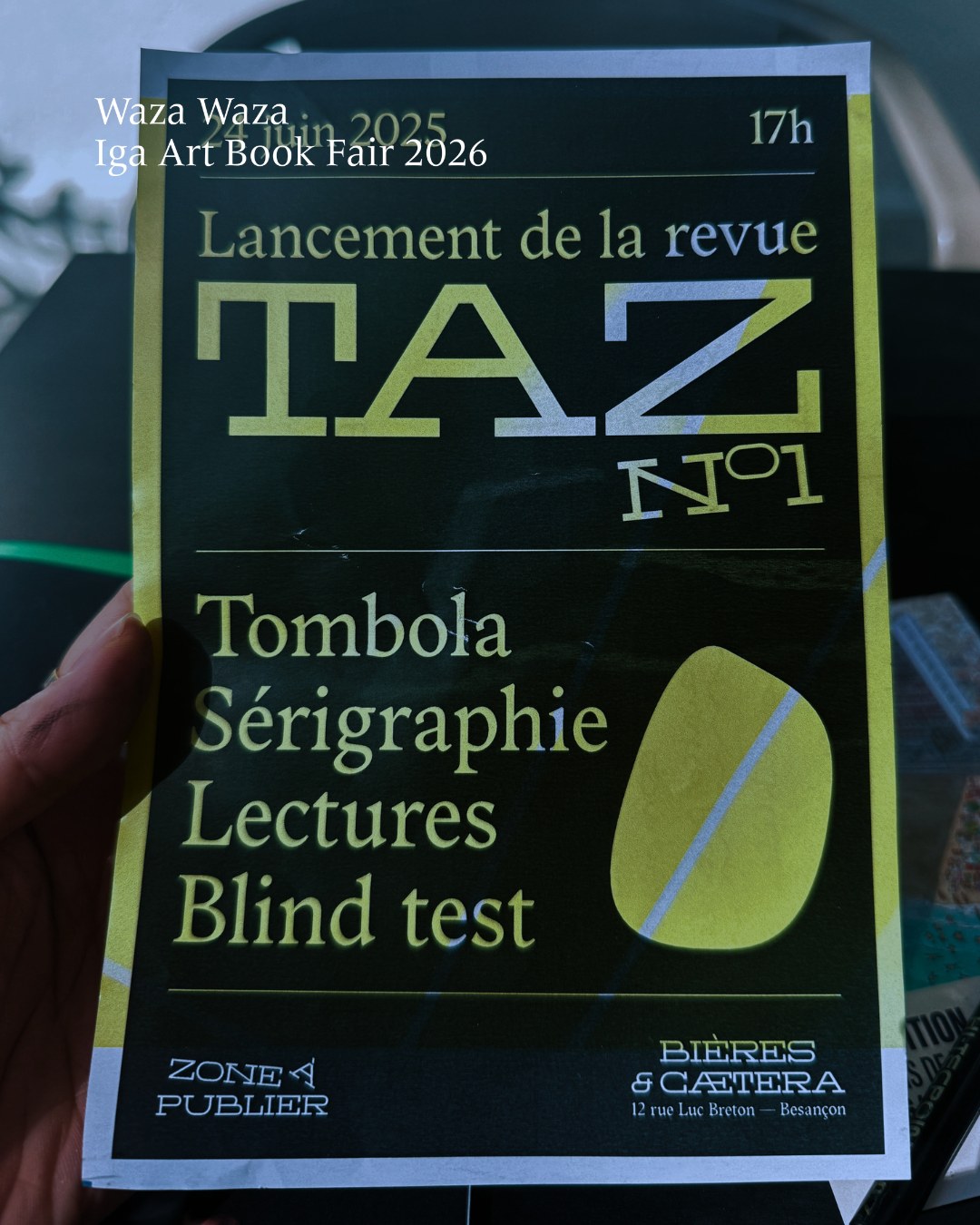 手に持たれた一枚のチラシ。雑誌 TAZ N°1 の刊行イベントの告知で、2025年6月24日17時、ブザンソンの Bières & Cætera と書かれている